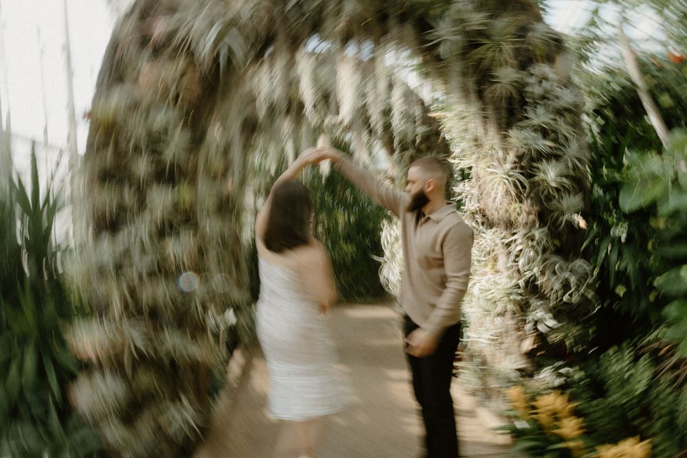A person in white clothing moves ethereally through a forest surrounded by lush greenery.