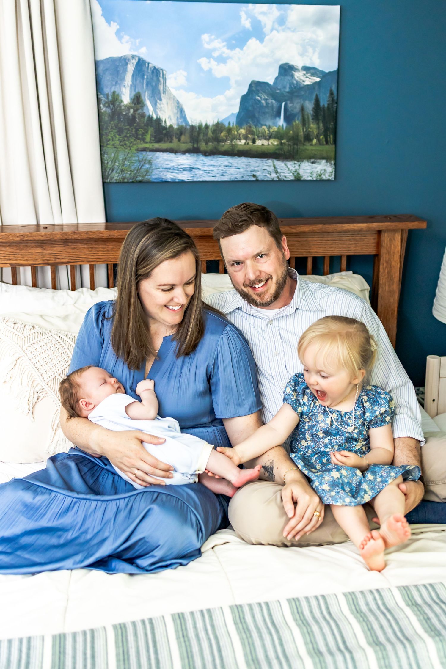 A family sits together on a bed with a newborn baby. Newborn photographer in richmond, virginia. RVA Photographer