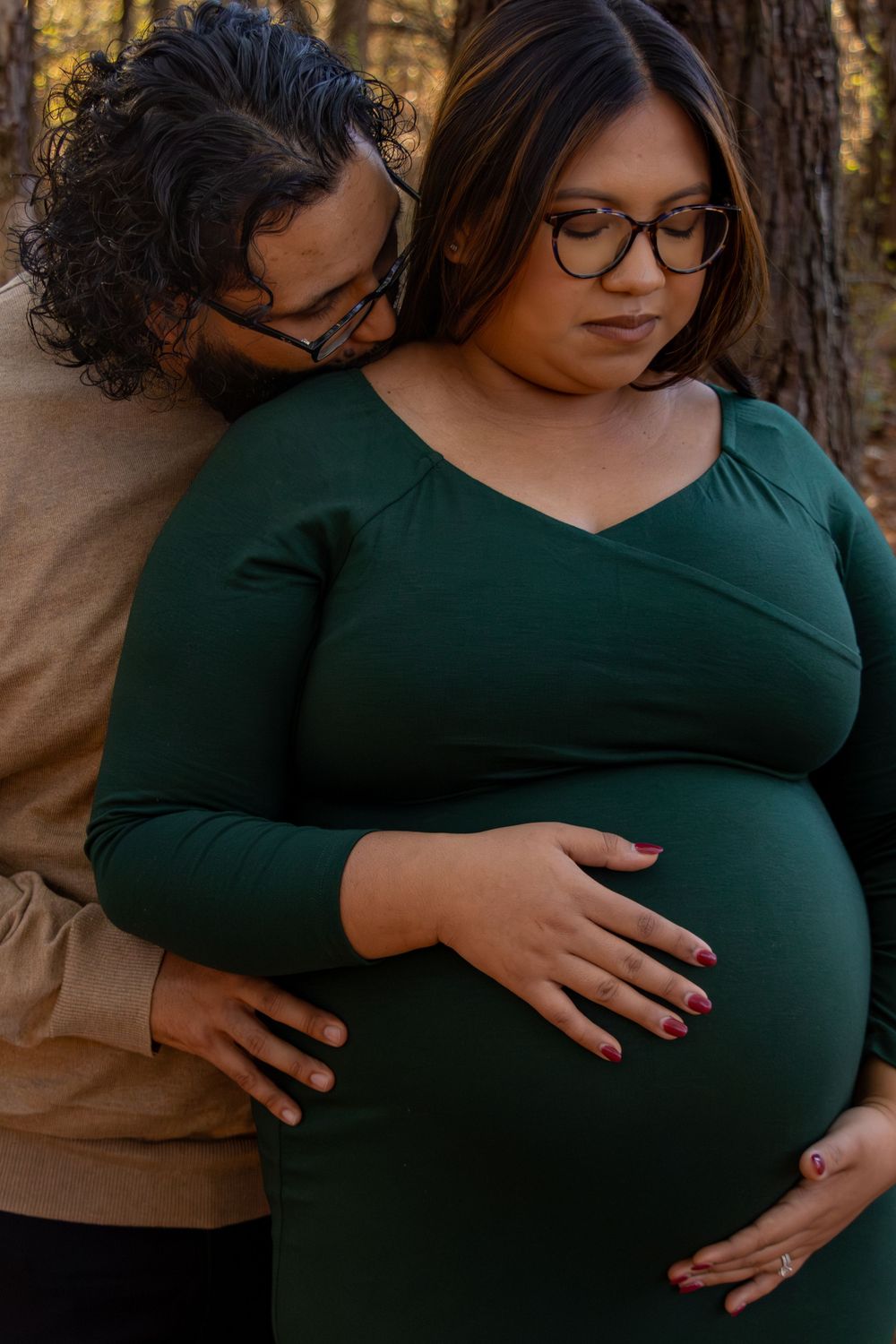 Close-up shots of loving embrace during maternity photoshoot in forest setting.