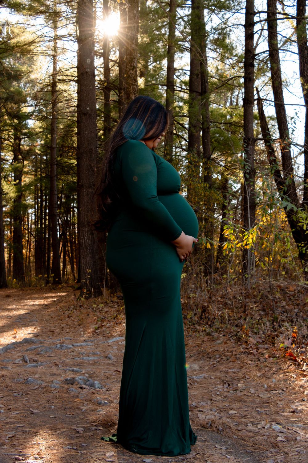 Sunlit forest scene with figure in emerald dress during golden hour photography session.