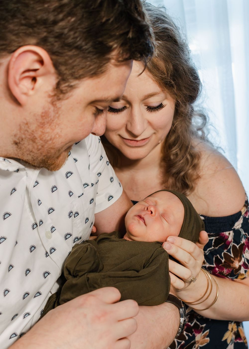 Intimate family moment with a sleeping baby in olive green clothing.