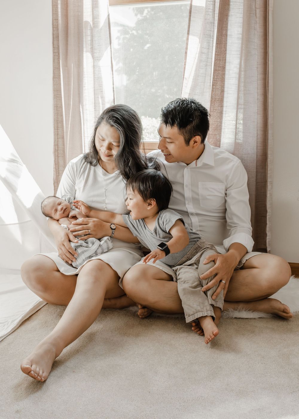 Natural light family photography showing tender interactions on carpeted floor.