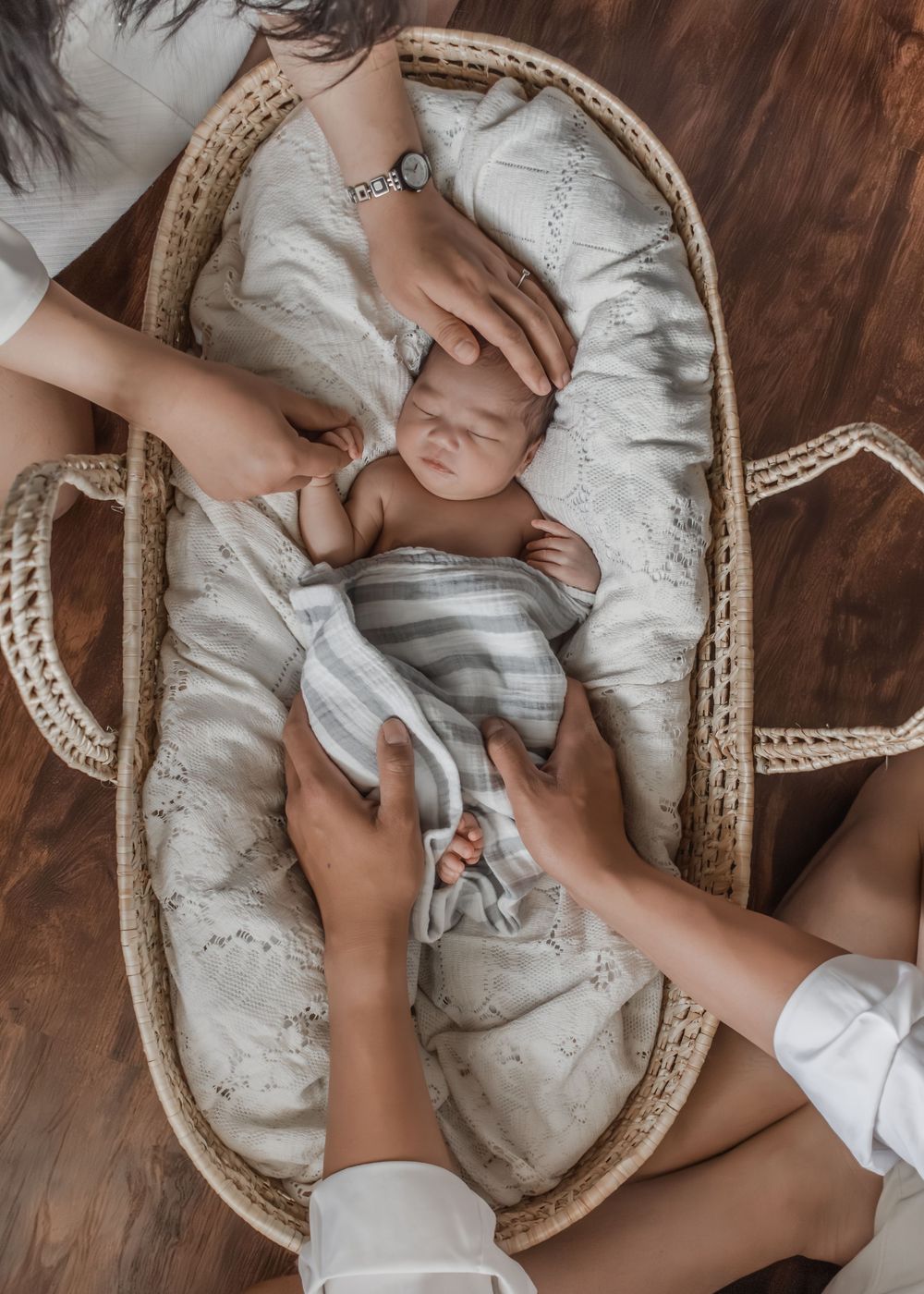 Baby resting peacefully in woven basket with soft gray bedding.