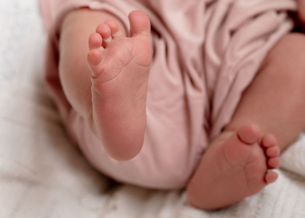 Close-up of baby's tiny feet in pink clothing against white background.