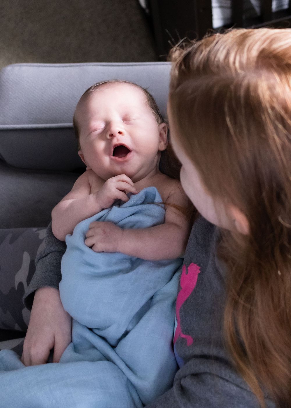 Young child interacting with sleeping baby in blue clothing.