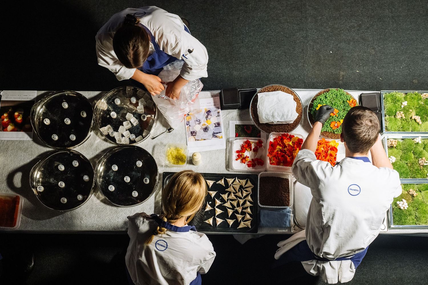 Chefs working at food preparation stations in a professional kitchen.