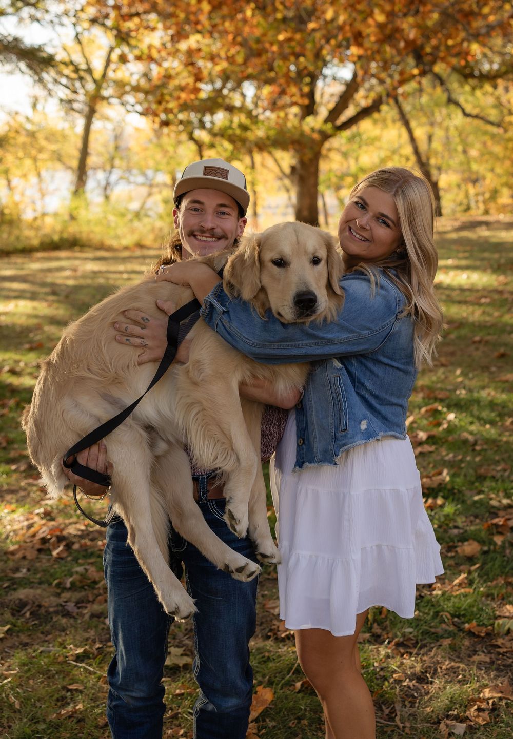 Playful moments with a golden retriever during autumn couple's photoshoot.