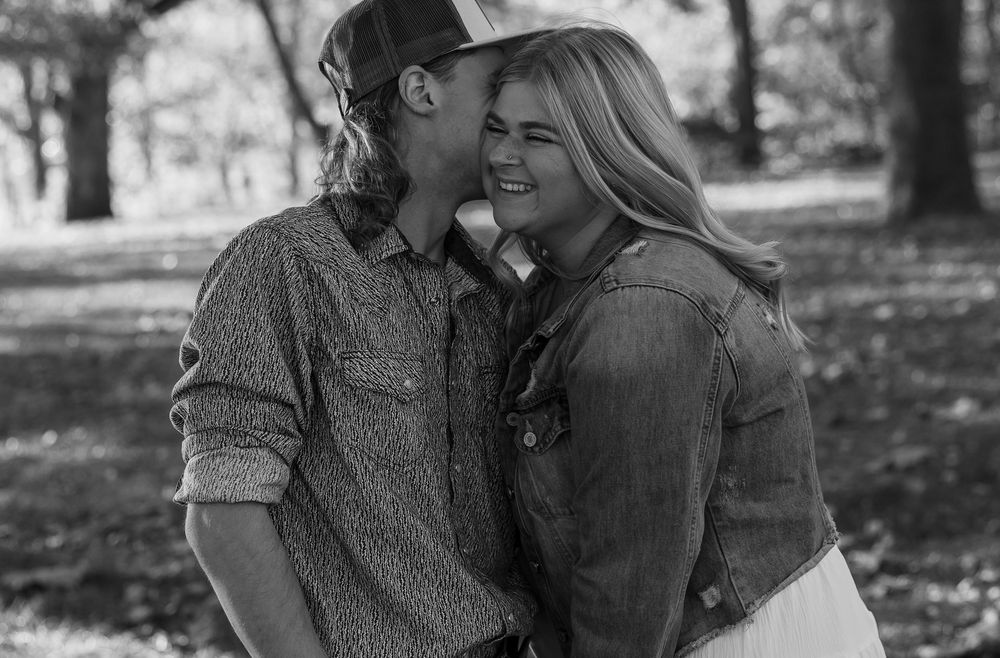 Black and white portrait of couple sharing tender moment outdoors.