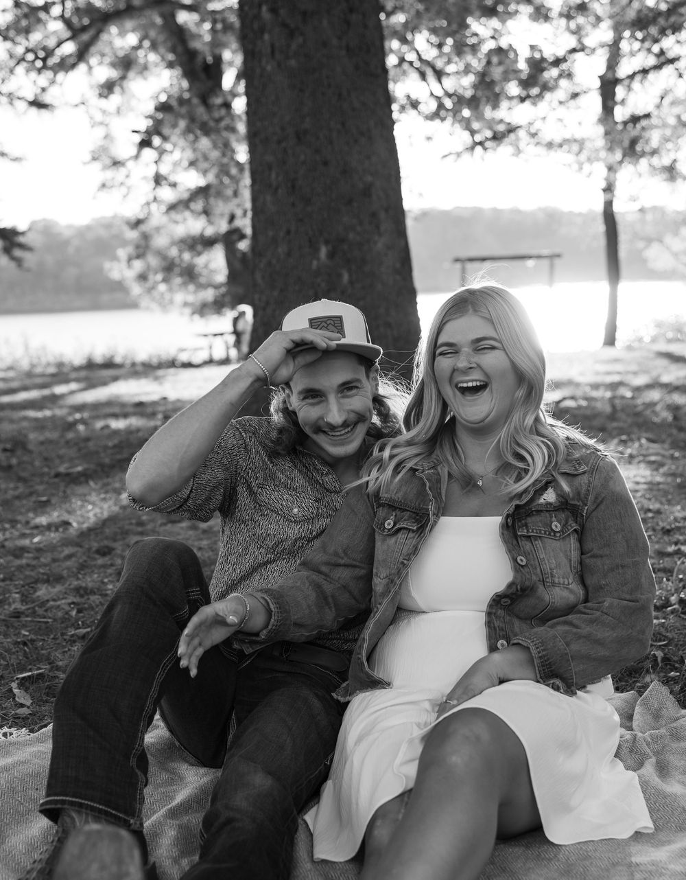 Black and white photo of a couple laughing while sitting outdoors.