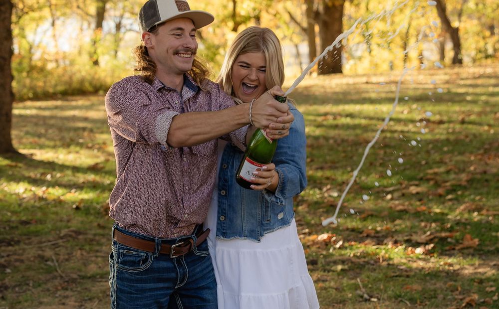Playful moment with champagne spray in an autumn park.