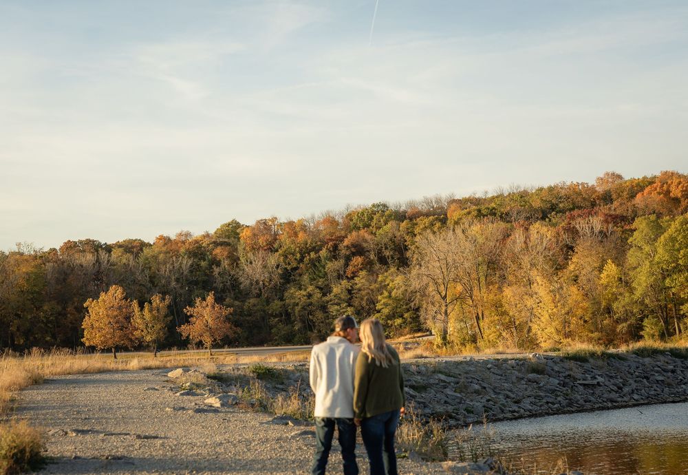 Scenic autumn landscape with trees and water along a rocky shoreline at sunset.