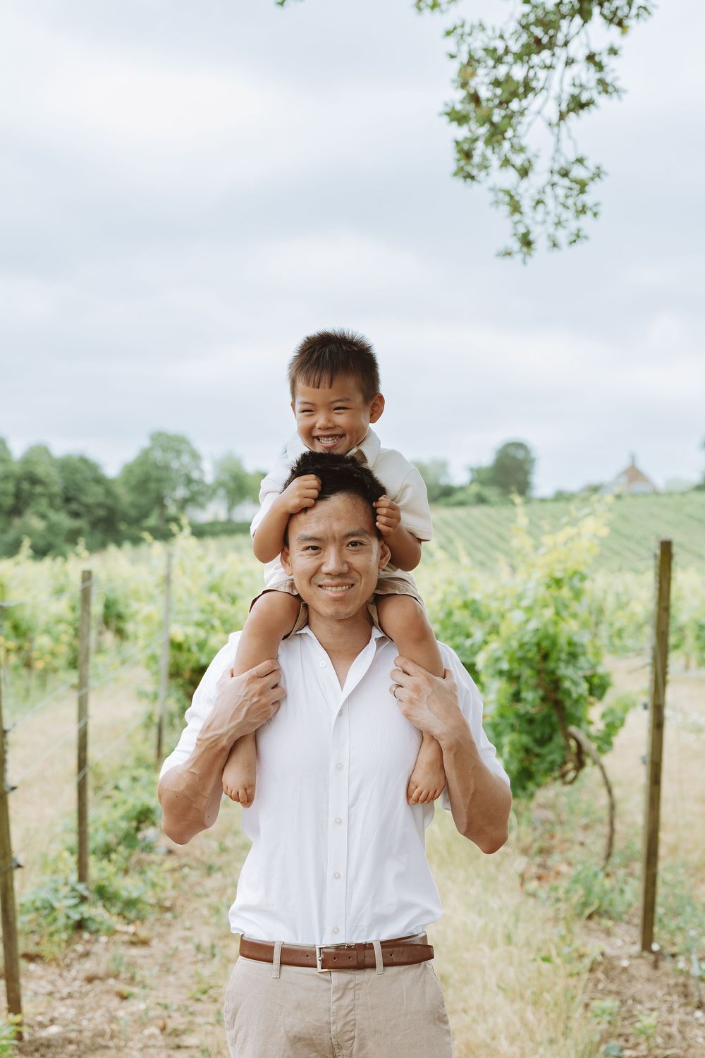 A joyful father and child spending time together outdoors in a vineyard on a sunny day.