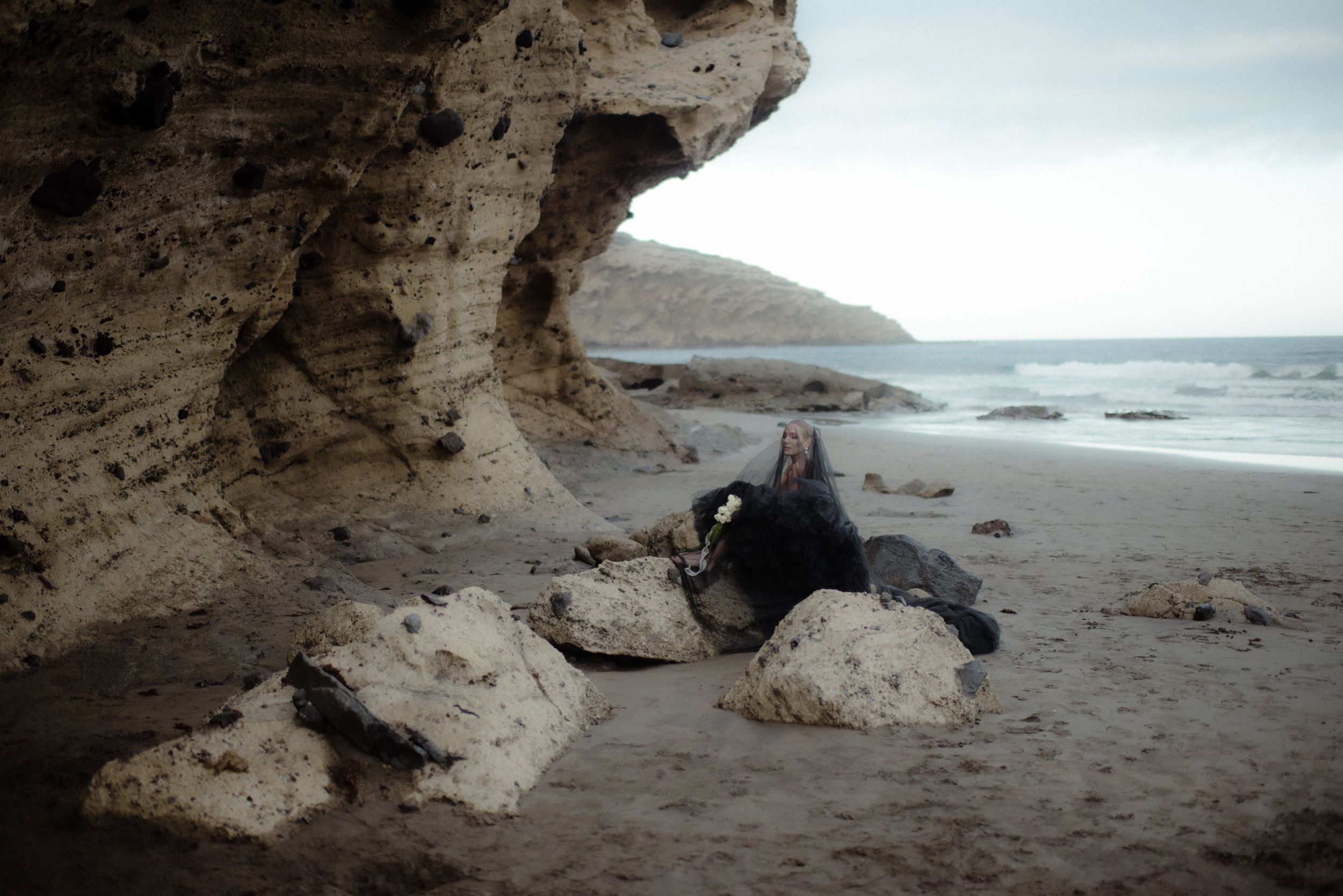 Scenic coastal panorama showing rugged cliffs and rock formations along a misty beach shoreline at Tenerife. Portrait photoshoot.