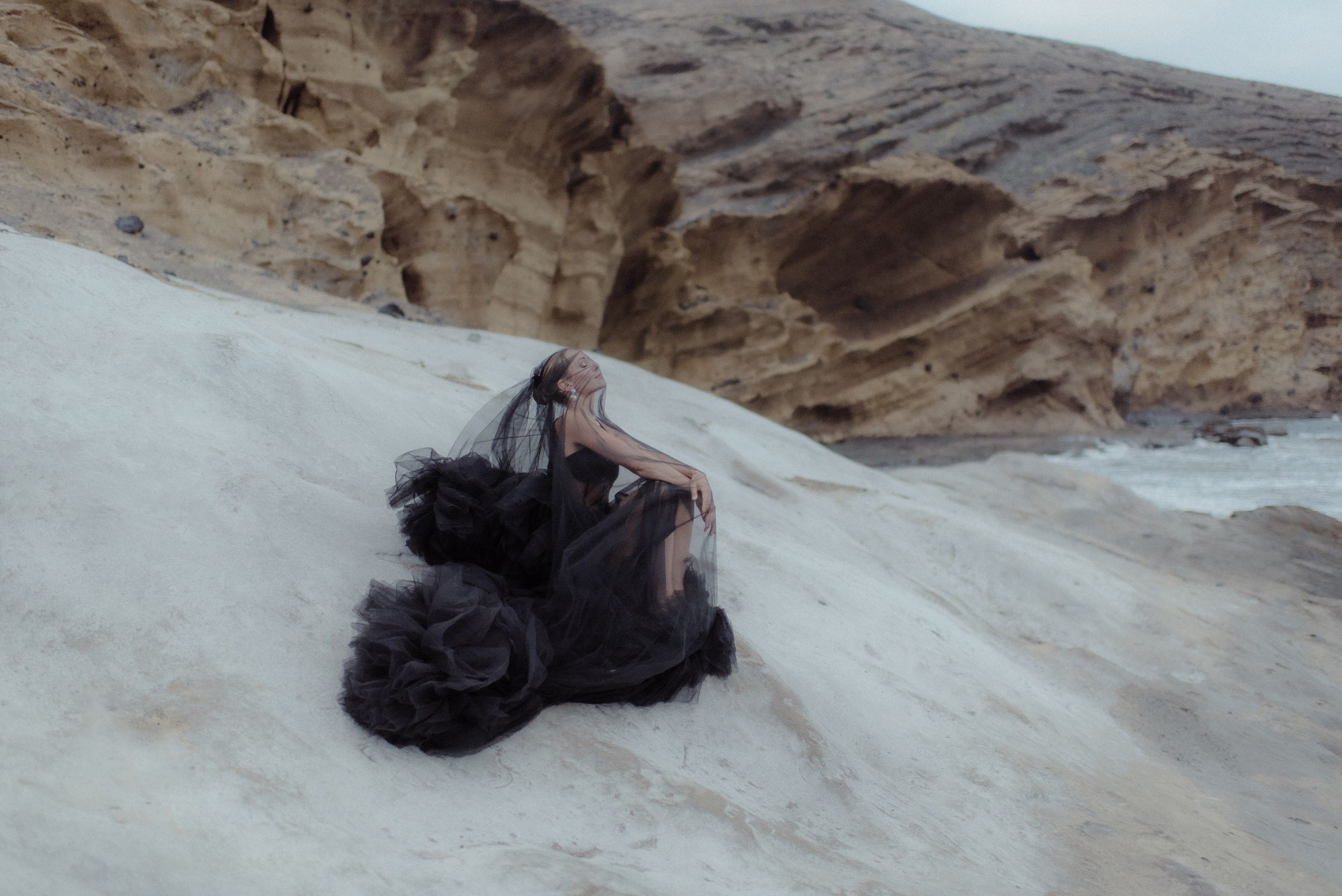 A sequence showing a figure in dark clothing moving across white desert sand formations against rocky cliffs in the south of Tenerife.