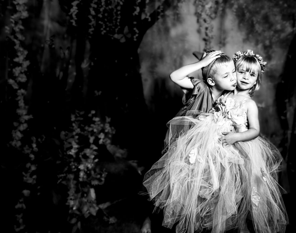 Black and white photos of a baby in a tutu dress posing in different positions against a dark background.