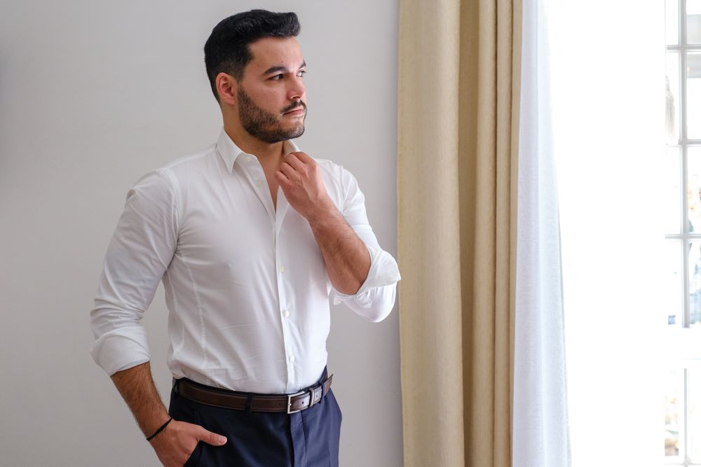 Man in white shirt looking contemplative in an elegant interior setting.