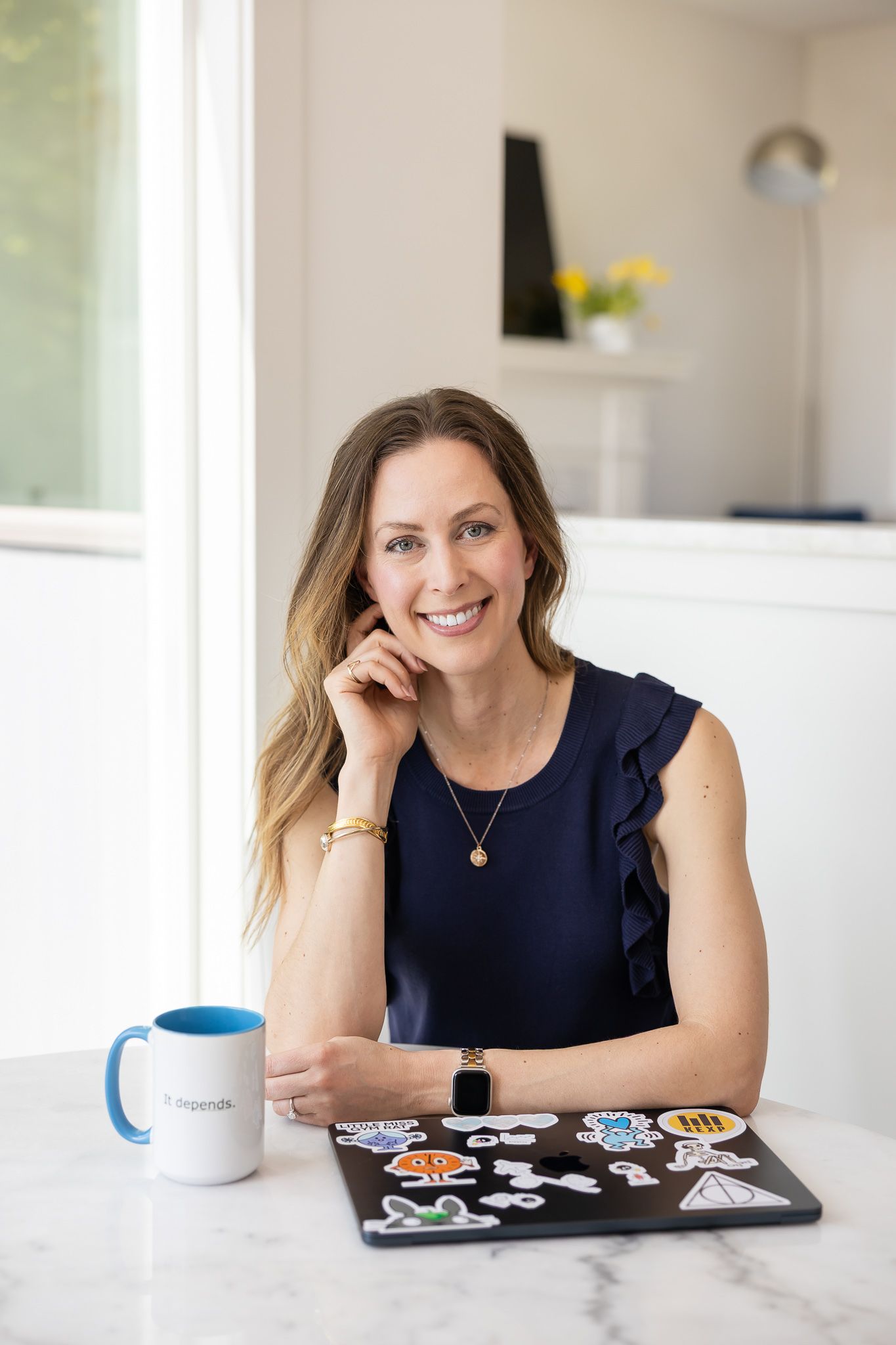 Jessica Stegner Seattle SEO consultant woman business owner branding sitting at table with laptop closed and coffee mug by elbow smiling