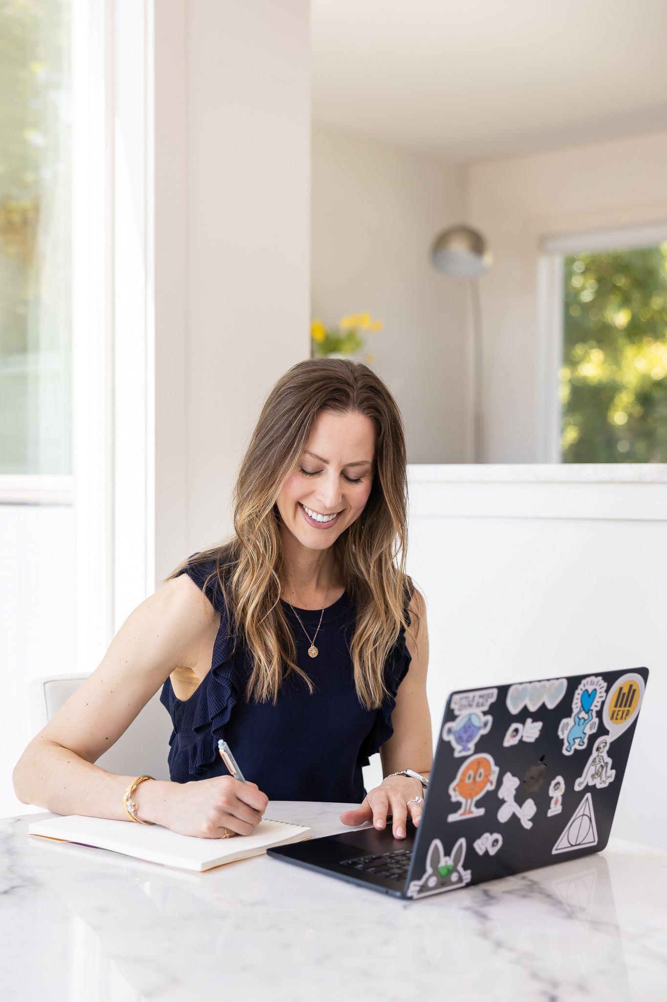 Jessica Stegner Seattle SEO consultant woman business owner branding sitting at table in kitchen taking notes in notebook while on computer