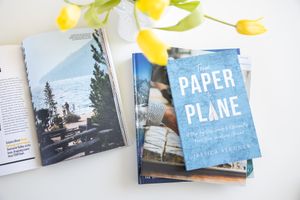 Jessica Stegner Seattle SEO consultant woman business owner branding overhead of travel magazines open spread and Paper Plane book
