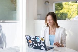 Jessica Stegner Seattle SEO consultant woman business owner branding zoom call sitting at table with laptop open in white blazer