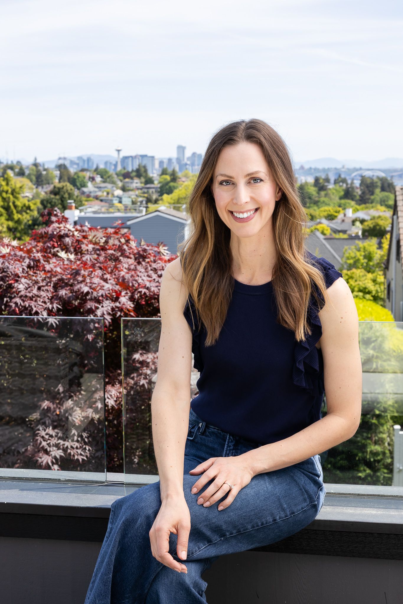 Jessica Stegner Seattle SEO consultant woman business owner branding sitting on patio with seattle skyline in background smiling