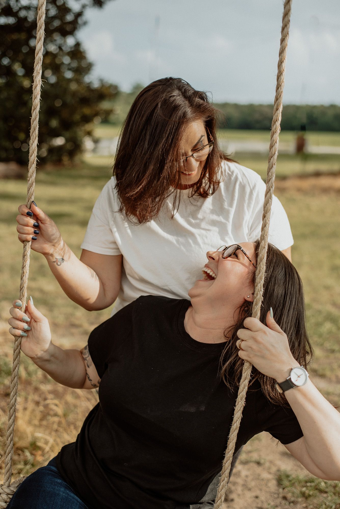 Playful moments shared on a rustic rope swing in a golden field.