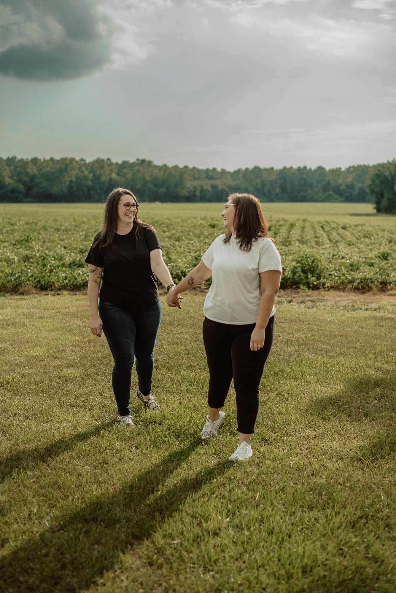 Friends walking together through a lush green field on a cloudy day.