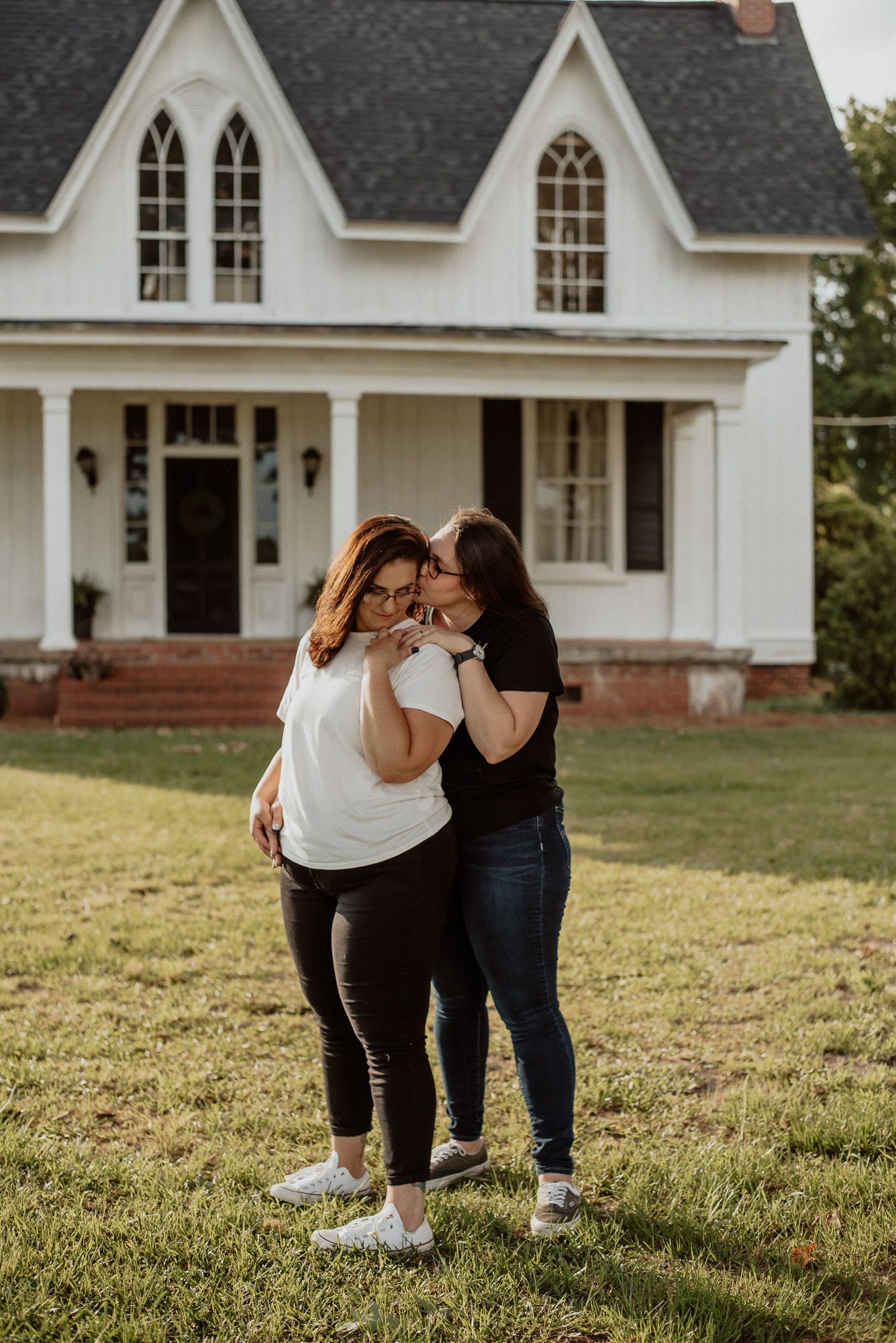 Candid moments captured outside a classic white farmhouse with black shutters.