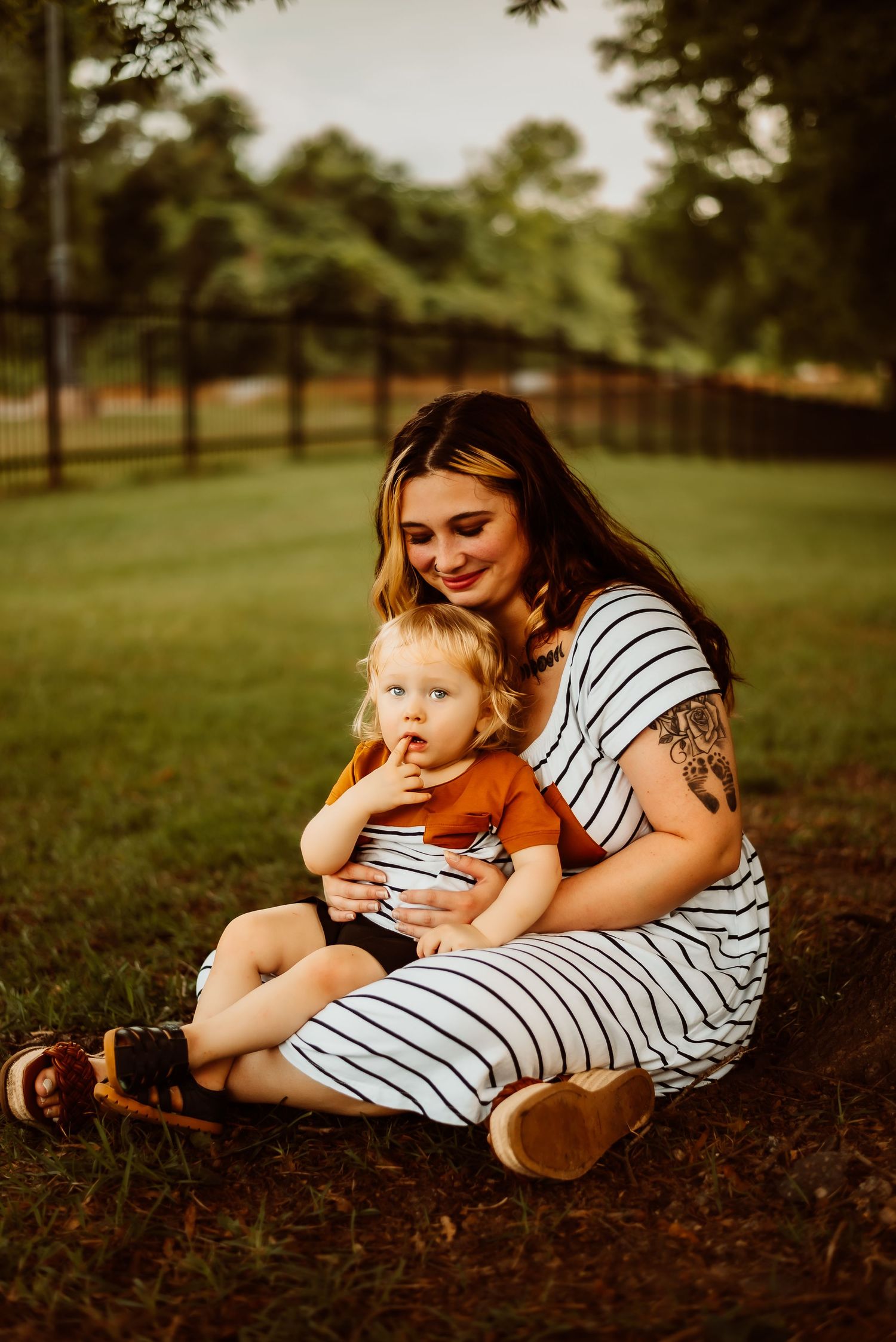 A tender moment captured outdoors on the grass with matching striped outfits.
