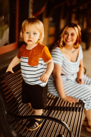 Striped outfits on metal bench during golden hour.