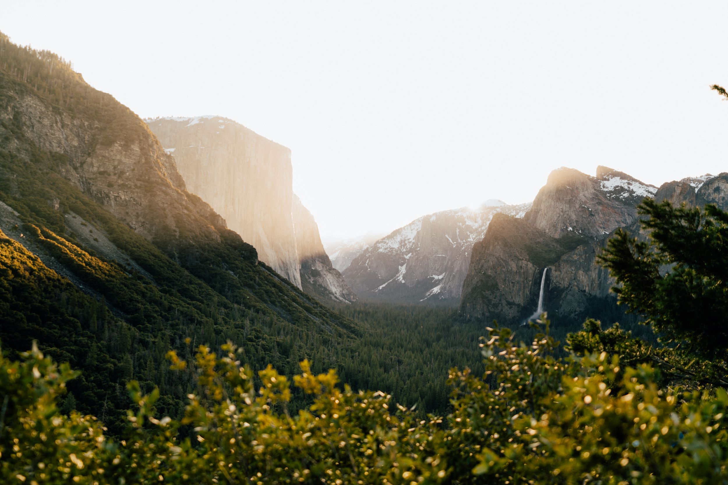 Majestic Yosemite Valley vista with towering granite cliffs and waterfalls in morning light.