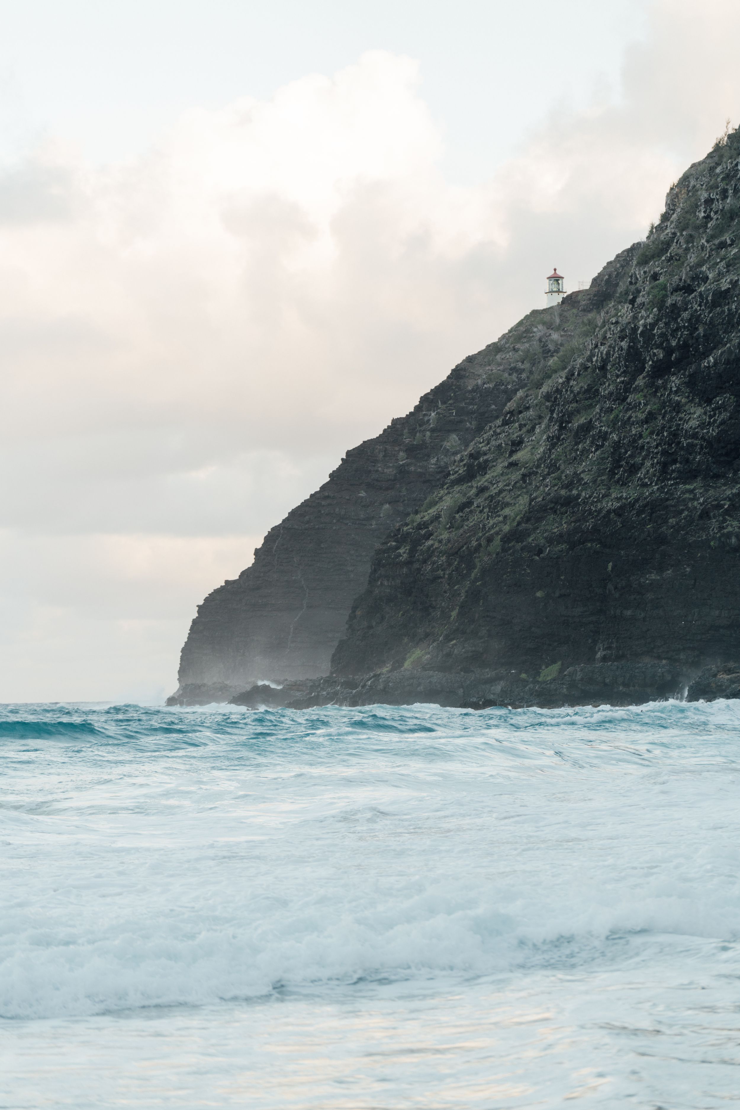 Dramatic coastal cliffs with crashing waves against a misty ocean backdrop.