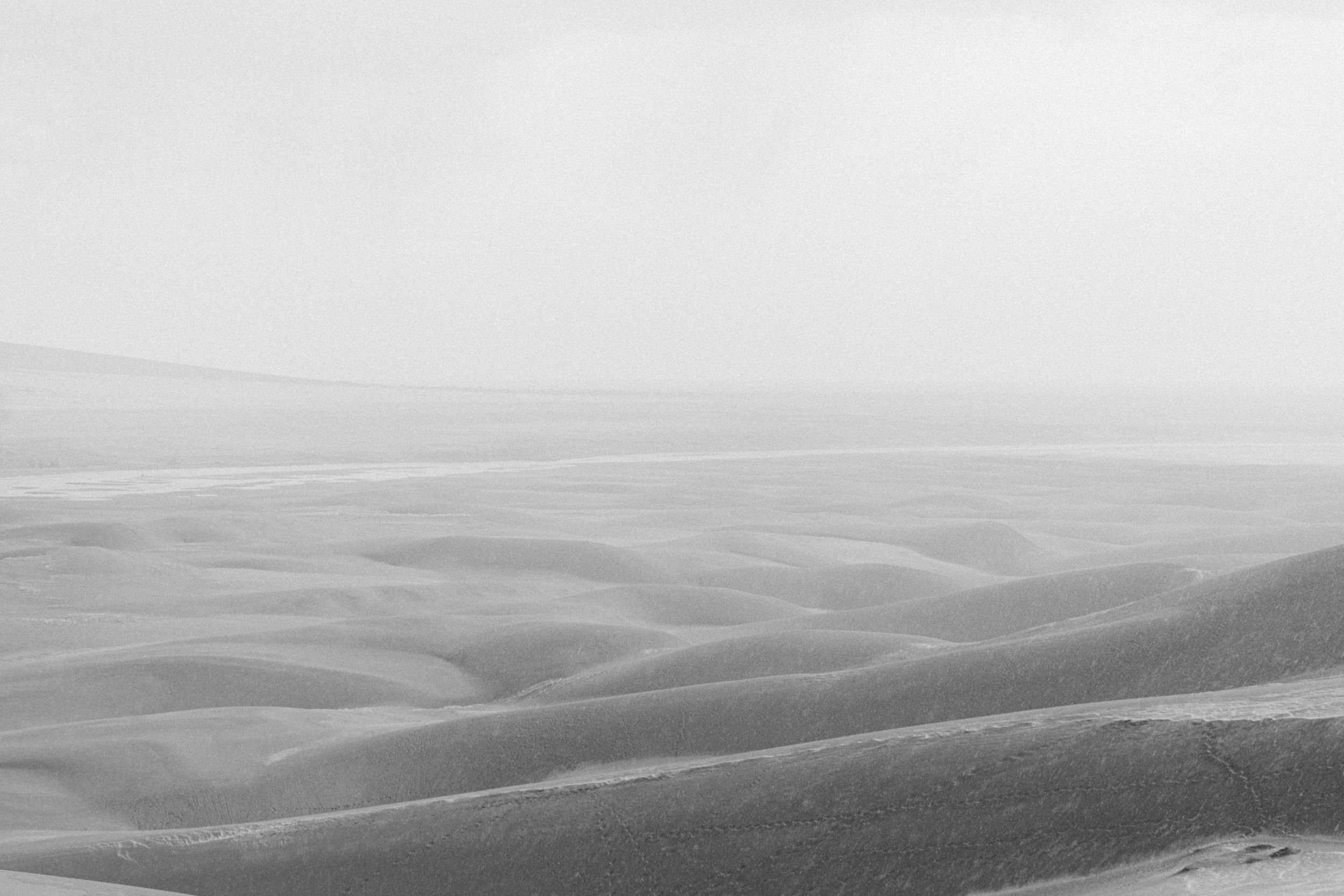 Rolling hills fade into misty horizon in black and white landscape.