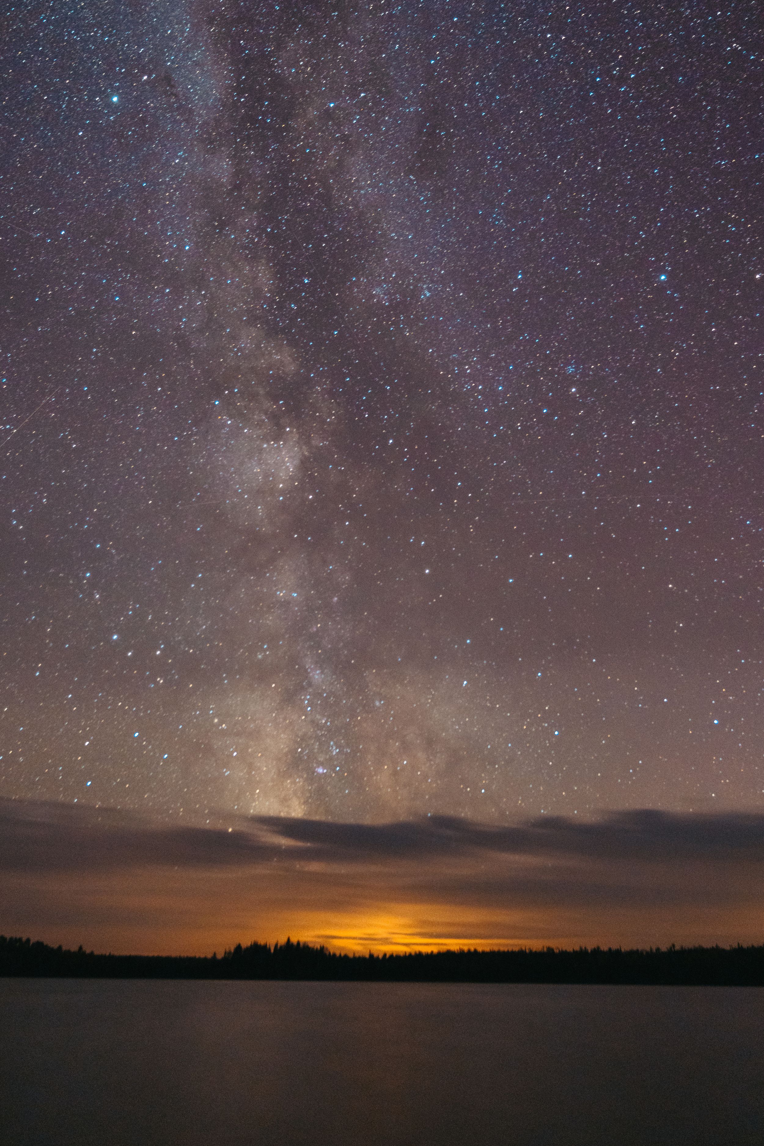Milky Way galaxy stretches across the night sky with glowing horizon.