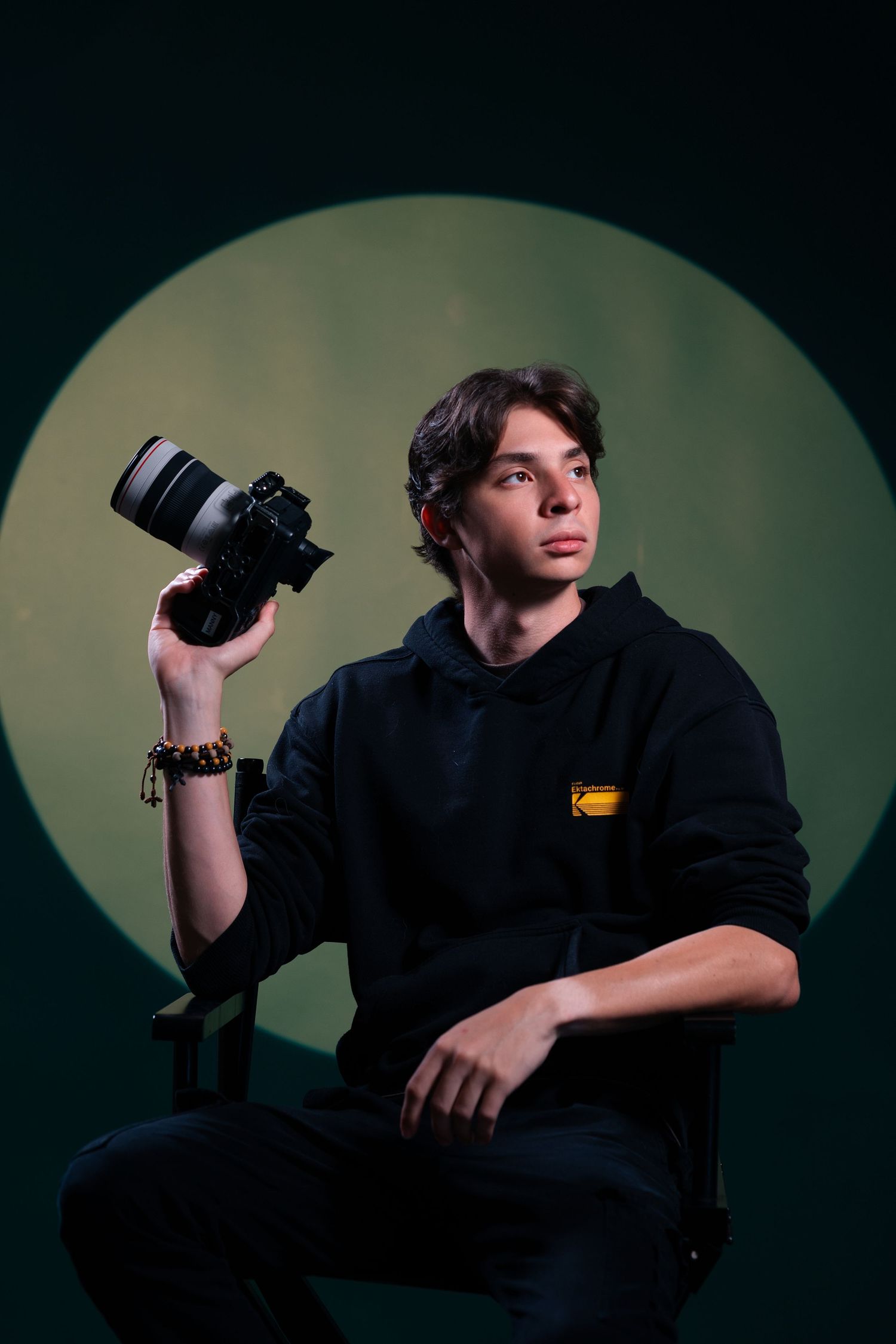 Young photographer holding a camera in front of a round spotlight backdrop, Miami portrait photographer | Mannyportraits