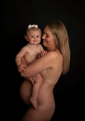Artistic portrait of parent and baby against dark background.