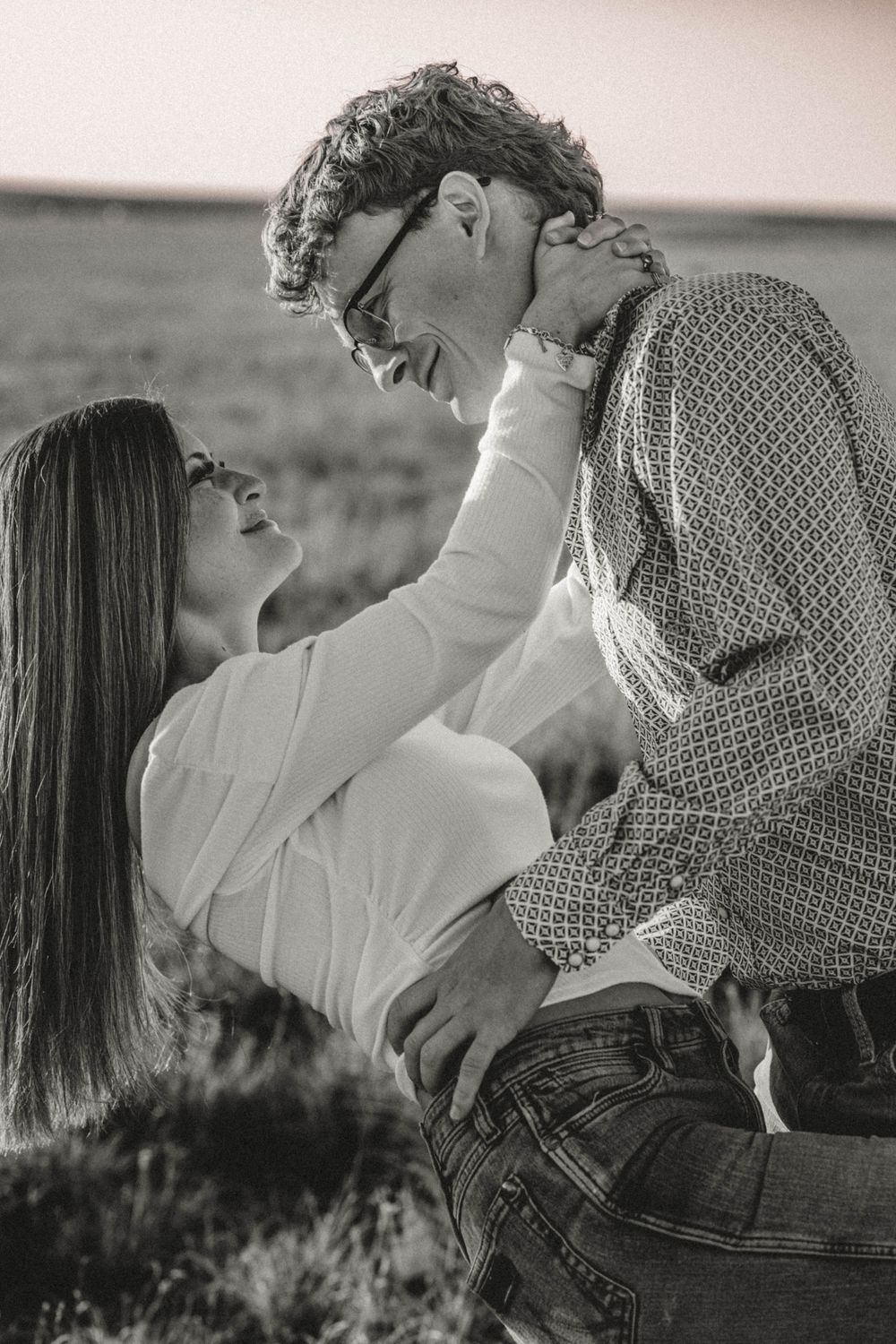 Black and white romantic portrait of a couple in an intimate moment outdoors in a field.