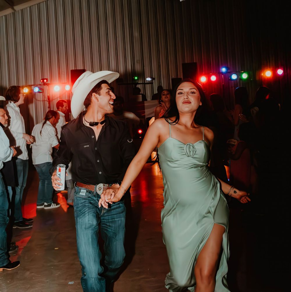 Wedding reception dance party with colorful lighting and guests dancing in a barn setting.