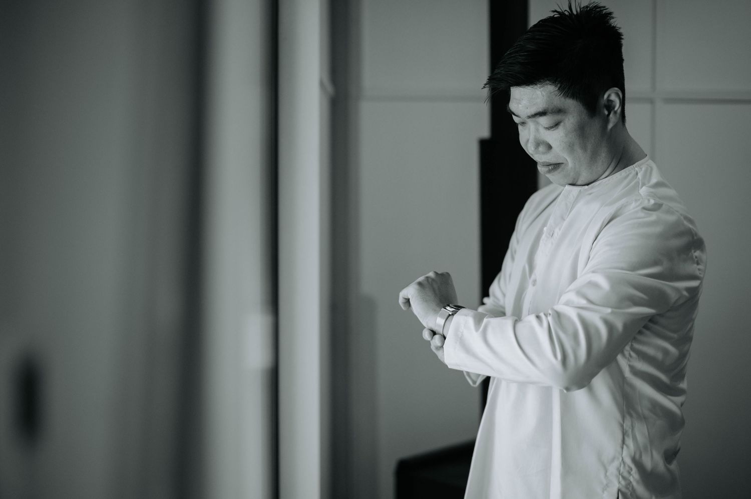 Black and white portrait of person checking watch while getting ready.