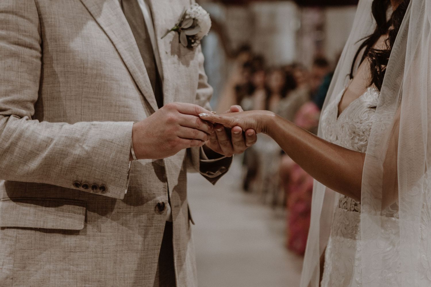Close-up of wedding ring exchange between couple during outdoor ceremony.