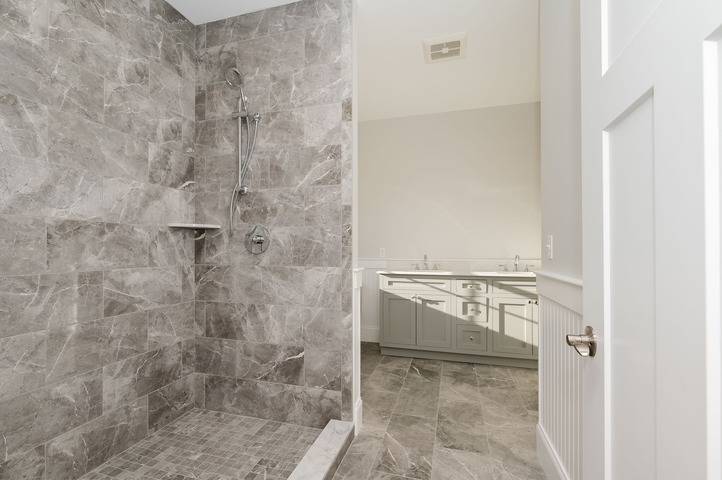 Modern bathroom featuring marble-look tile shower enclosure and sleek fixtures.