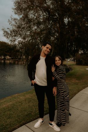 A couple enjoys a casual autumn stroll along a waterfront path.