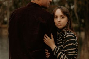 Two people in casual attire share an intimate moment during a fall photoshoot.