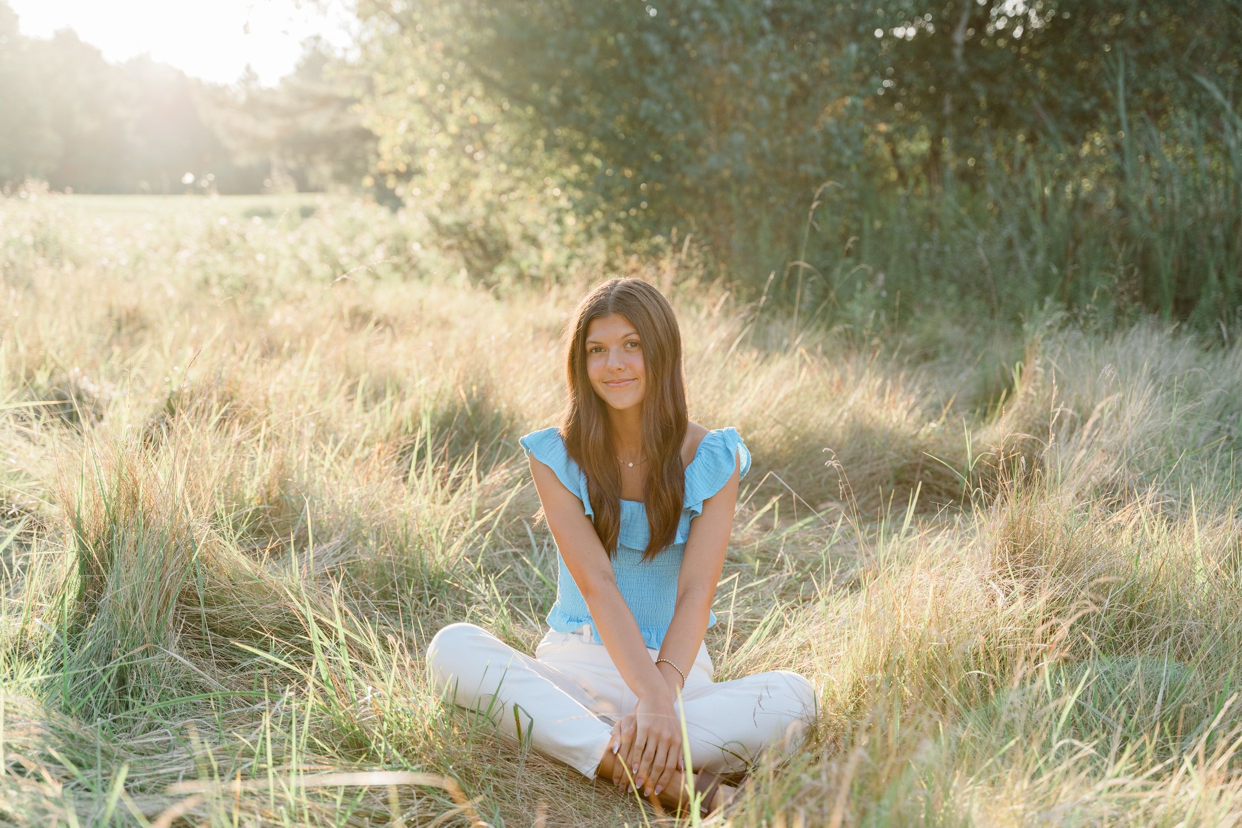 A dreamy golden hour photoshoot in tall grass with soft natural lighting and ethereal atmosphere.