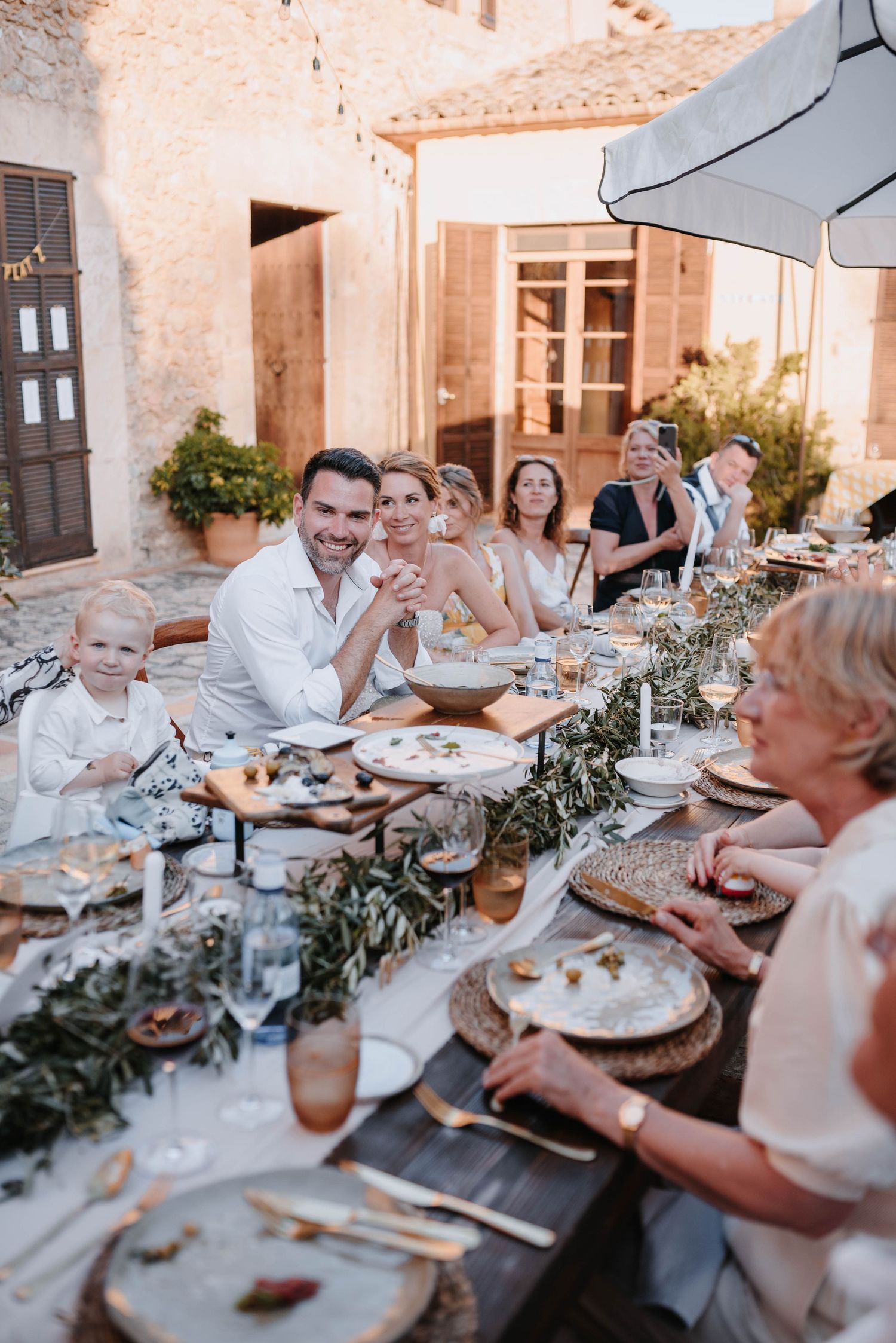 Die Menschen versammelten sich in der Abenddämmerung um einen rustikalen Esstisch im Freien und genossen gemeinsam ein Hochzeitessen.
