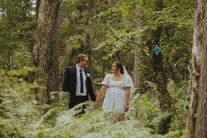 Wedding couple walking through a scenic forest path surrounded by greenery.