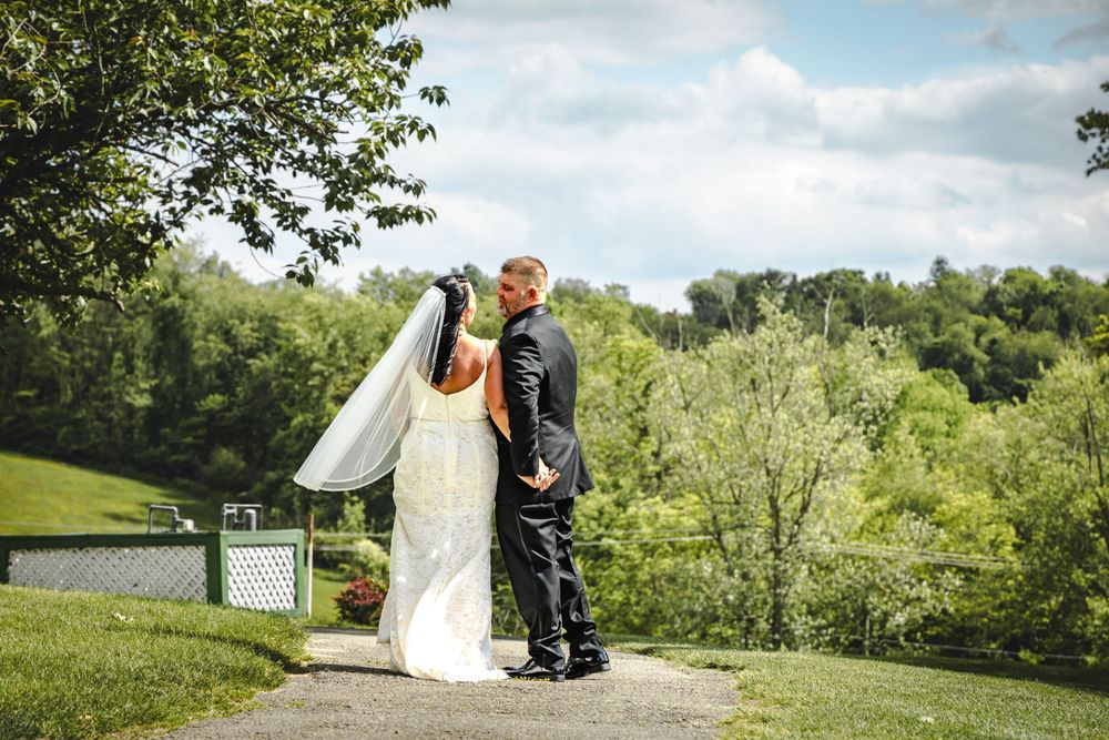 A couple shares an intimate moment on a grassy hill during their outdoor wedding ceremony.