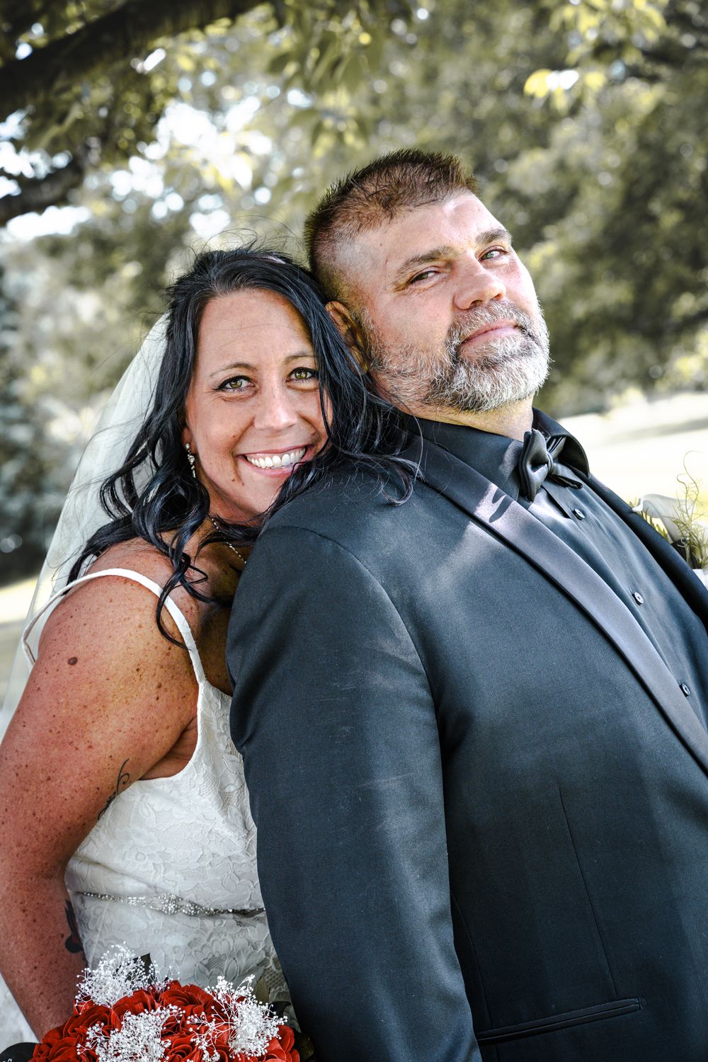 A happy wedding couple embraces outdoors while sharing a joyful moment together.