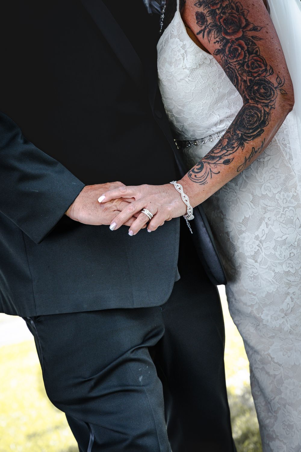 Close-up of ornate floral tattoo art on an arm against formal wedding attire.