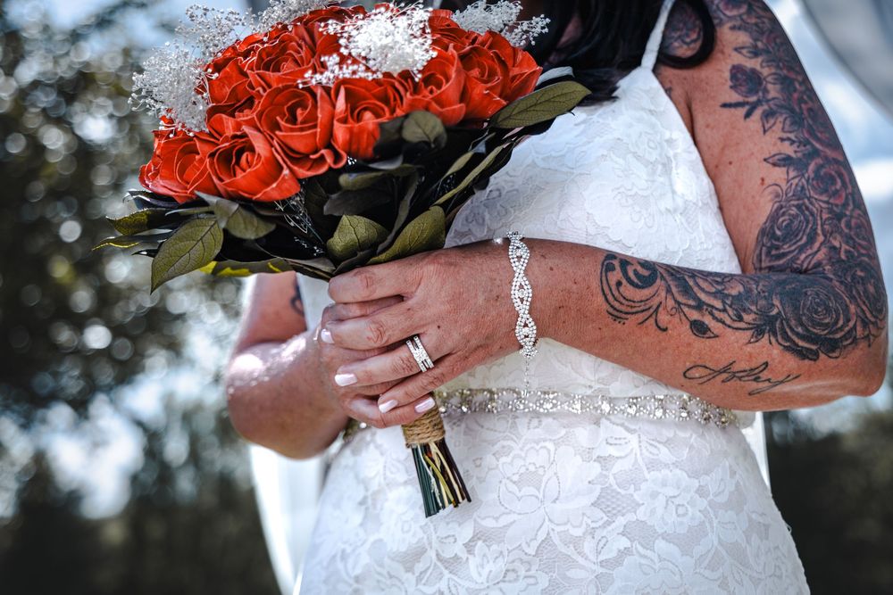 Vibrant red rose wedding bouquet held against a white lace dress.